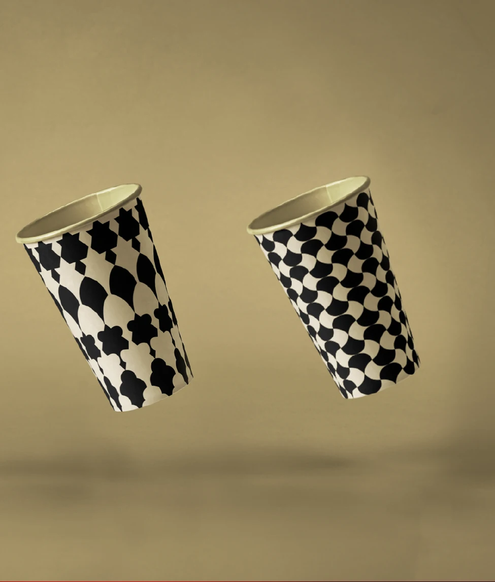 Two ASTRA takeaway cups wrapped in the black and cream pattern